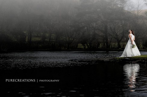 Bride in white by lake  in Craig y Nos Country Park