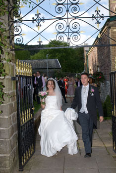Bride and Groom walk through gate from theatre gardens Bride and Groom walk through gate from theatre gardens at Craig y Nos Castle Wedding Venue in Wales
