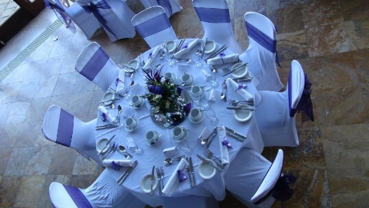 Craig y Nos Castle Wedding Venue in Wales table laid up for wedding breakfast with white chair covers and table linen