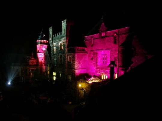 See the contrast in colours here, the clock tower roof black, the castellated section grey stone, and plenty of purple Craig y Nos Castle Wedding Venue Swansea Floodlit at Night in purples and greys