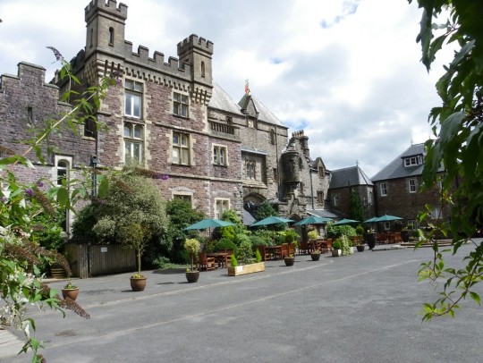 Larger castellated section of Craig y Nos was built after 1878 which gives rise to it being called a 'Castle' Craig y Nos Castle Wedding Venue Swansea Front facade of castle with potted plants and tables and chairs