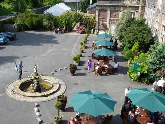 Taken from one of the bedrooms, looking down on the front courtyard's chairs and awnings over tables Craig y Nos Castle Wedding Venue Swansea Front Courtyard on a warm summers day