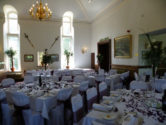 Evening Function room looking towards front of castle (swords on wall) with theatre doors to right Craig y Nos Castle Wedding Venue in South Wales showing function room laid up for a wedding breakfast